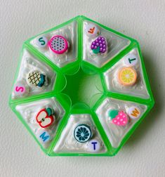 a green and white plastic toy with different items on it's sides in the shape of a hexagon