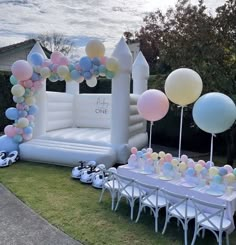 an inflatable arch with balloons and other decorations on the lawn at a birthday party