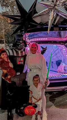 some people are dressed up as darth vader and princess leis in front of a star wars vehicle