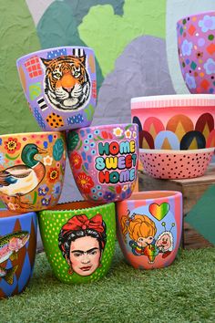 there are many colorful bowls on the ground with faces painted on them and one has a tiger