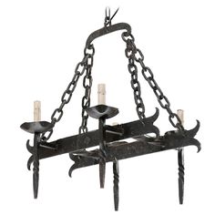 an iron chandelier with five candles hanging from it's arms and chains