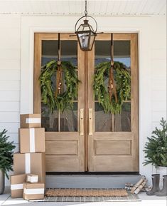 two wreaths on the front door of a house with boxes stacked in front of them