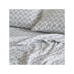 an unmade bed with white sheets and black flowers on the comforter is shown