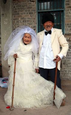 an older couple dressed in wedding attire posing for the camera with their canes on