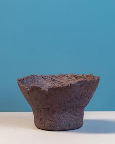 a brown bowl sitting on top of a white table next to a blue wall with a bird perched on it