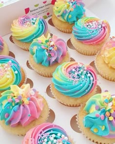 cupcakes with rainbow frosting and sprinkles in a box