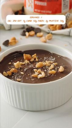 a white bowl filled with chocolate and nuts on top of a table next to a can of milk