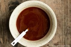 a white bowl filled with brown liquid on top of a wooden table