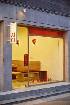 an empty bench sits in the window of a storefront at night with its lights on