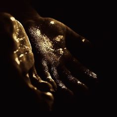 a person's hand covered in powder on a black background with the light shining through it