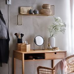 a wooden desk topped with a mirror next to a vase filled with flowers and other items