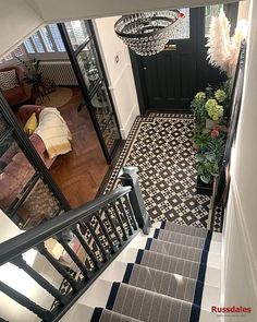 the stairs lead up to an entryway with chandelier and potted plants