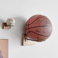 a basketball mounted to the wall next to two framed pictures and a wooden block with an autographed basketball on it