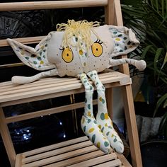 a stuffed animal sitting on top of a wooden chair next to a potted plant