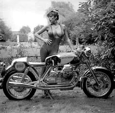 a woman in a bathing suit standing next to a motorcycle