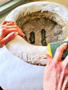 two hands are sanding up the base of a potted plant with a sponge