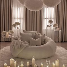 a living room filled with lots of candles and pillows on top of a white rug