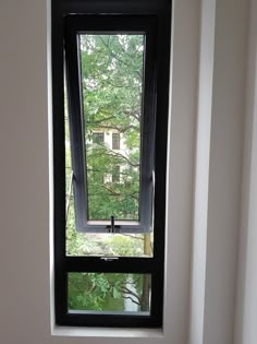 a bathroom window with the view of trees outside in front of it on a sunny day