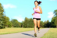 a woman running down a road in the grass