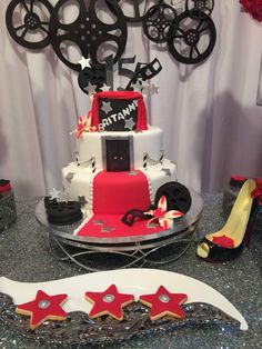 a red and white cake sitting on top of a table next to high heel shoes