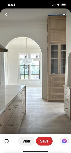 an image of a kitchen with white counter tops and wooden cabinets in the middle, along with a large arched doorway leading to another room