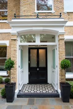 a black and white tiled entry way with potted plants on either side of the door