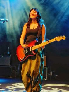 a woman standing on stage with a guitar