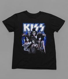 Immerse yourself in the legendary energy of KISS with this epic Rock Music T-Shirt! Welcome to Poster Kingz, your ultimate destination for T-shirt enthusiasts and pop culture aficionados! We take immense pride in curating a captivating collection of T-shirts inspired by your favorite films, beloved TV shows, and iconic music artists. Quality and Comfort:Our T-shirts are crafted with the utmost care, using premium materials to ensure comfort and durability. Made from soft, breathable fabric, these tees are perfect for everyday wear or as a statement piece to showcase your passion for pop culture. Film, TV, and Music Delights:Indulge in nostalgia and relive memorable moments with our diverse range of T-shirts. From classic movie quotes to iconic TV show references, and legendary music band a Pop Culture Graphic Print T-shirt For Concert, Unisex Rock And Roll T-shirt For Streetwear, Rock And Roll Band Logo T-shirt For Fans, Black Music-themed T-shirt With Sublimation Print, Band Merch T-shirt With Graphic Print For Fans, Unisex Alternative Style T-shirt For Fan Merchandise, Band Merch Graphic Print T-shirt For Fans, Alternative Style Pre-shrunk T-shirt For Music Festivals, Rock And Roll Band Logo T-shirt For Streetwear