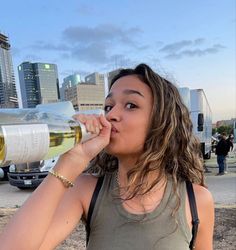 a woman drinking from a wine glass in front of a city skyline