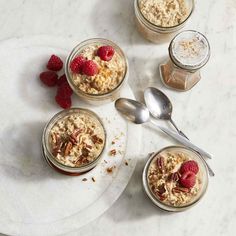 three jars filled with oatmeal and raspberries on a white plate