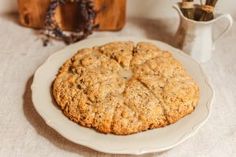 an oatmeal cookie sitting on top of a white plate next to a cup