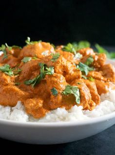 a white bowl filled with rice covered in sauce and garnished with cilantro