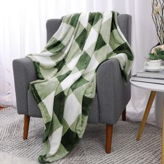 a green and white blanket sitting on top of a chair next to a coffee table