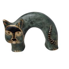 a green ceramic cat head with black and gold details on it's face, against a white background