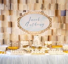 a table topped with lots of desserts next to a wall covered in book pages