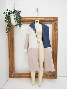 a mannequin is standing next to a wooden frame with a plant in it