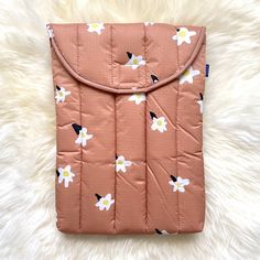 a pink and white flowered ipad case sitting on top of a furnishing