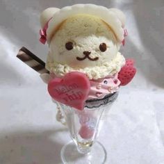 a small stuffed animal in a wine glass filled with ice cream and pink heart shaped candies