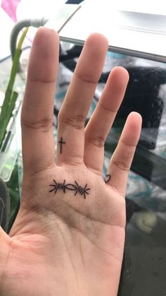 a person's hand with an arrow and cross tattoo on the middle of it