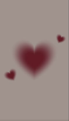 two red hearts floating in the air on a gray background with some blurry ones