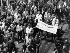 a large group of people standing on the side of a road with a sign in front of them