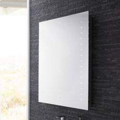 a bathroom sink sitting under a mirror next to a wall mounted faucet in front of a black tiled wall