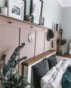 a bed with pillows and blankets in a bedroom next to a wall filled with pictures