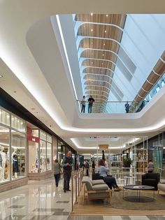 people are walking around in a mall with high ceilings and glass windows on the ceiling