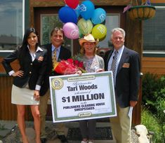 four people standing in front of a house holding a large check for $ 1 million