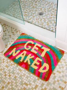 a colorful bathroom rug with the words get weird on it in front of a toilet