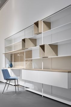 an empty room with shelves, chairs and a blue chair in the foreground is a white wall