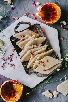 several pieces of flatbread on a tray with flowers and herbs around it, along with other food items