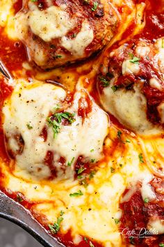 some meatballs covered in sauce and cheese on a pan