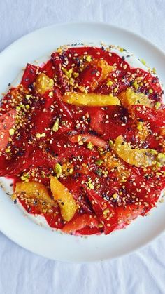 a white plate topped with fruit covered in sauce and sprinkles on top of a table